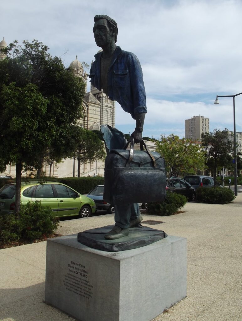 Statue représentant un ouvrier portant une valise, avec des parties de corps manquantes.