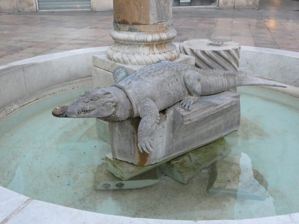 Le crocodile en pierre sur la fontaine de la Place du Marché.
